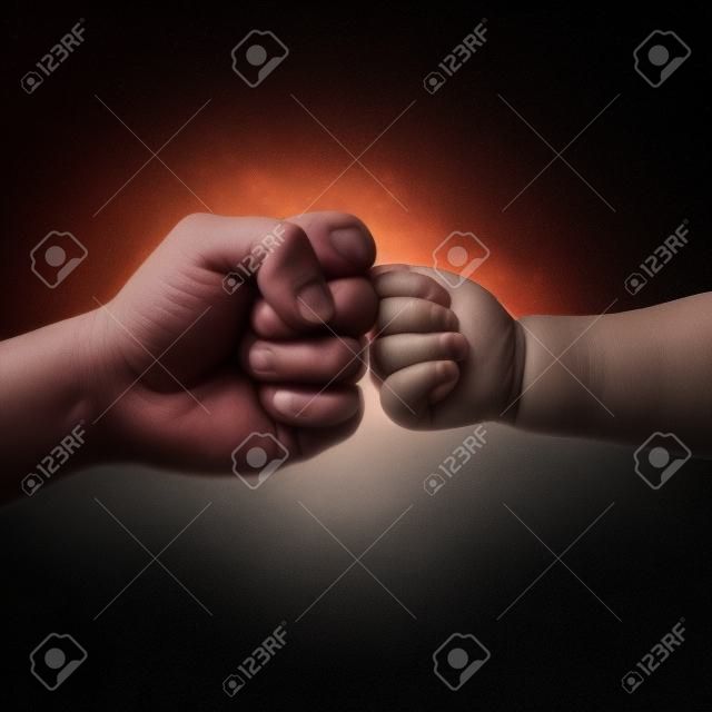 ojciec i dziecko dotykają pięści na czarnym tle
