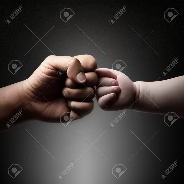 father and child touching fist on black background