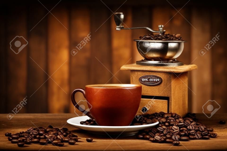 Stilleben mit Kaffeebohnen und alte Kaffeemühle auf dem hölzernen Hintergrund