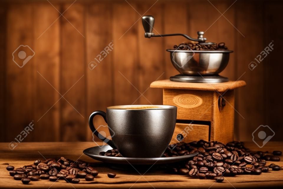 Todavía vida con los granos de café y molino de café antiguo en el fondo de madera