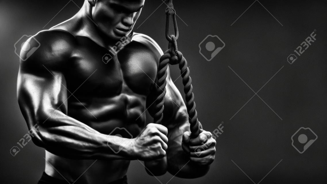 close up of healthy fit sporty man doing rope extension exercise, dramatic black and white image