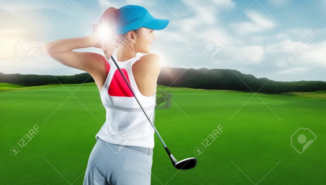 Jonge vrouw in sportkleding golfen op groen veld. Actieve frisse blanke vrouw swingen met golfclub.
