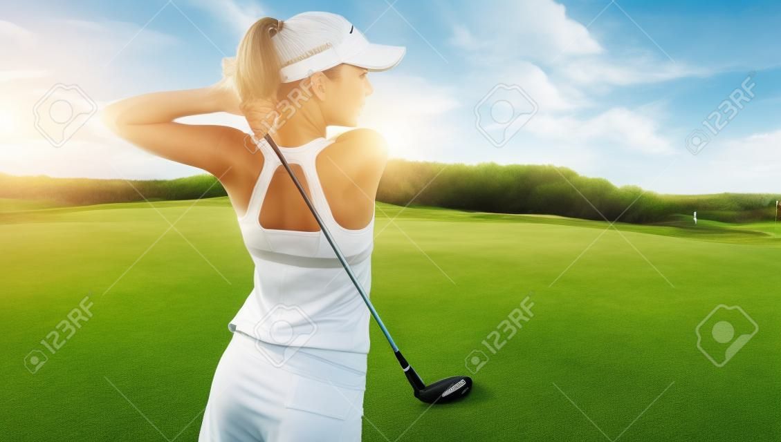 年轻女性在运动服打高尔夫在绿色领域活跃新鲜白人妇女与高尔夫球杆摆动