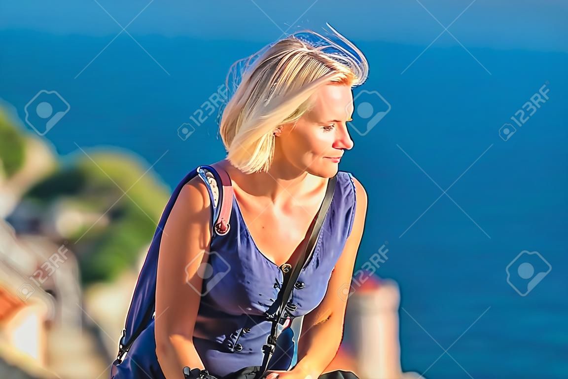 Young female traveler looks to the old city and sea from mountain in Dubrovnik. Croatia.