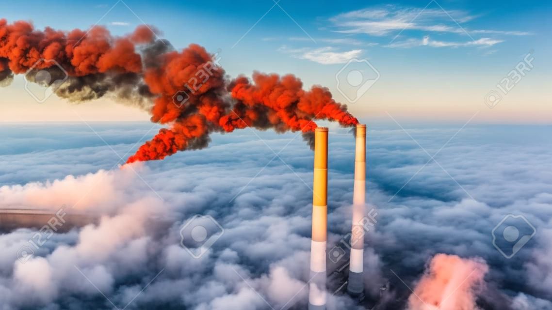 Air pollution by smoke coming out of two factory chimneys. Aerial view