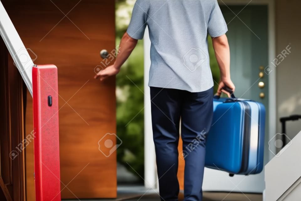 Ein Mann mit einem Koffer über den Fuß aus der Tür seines Hauses zu reisen