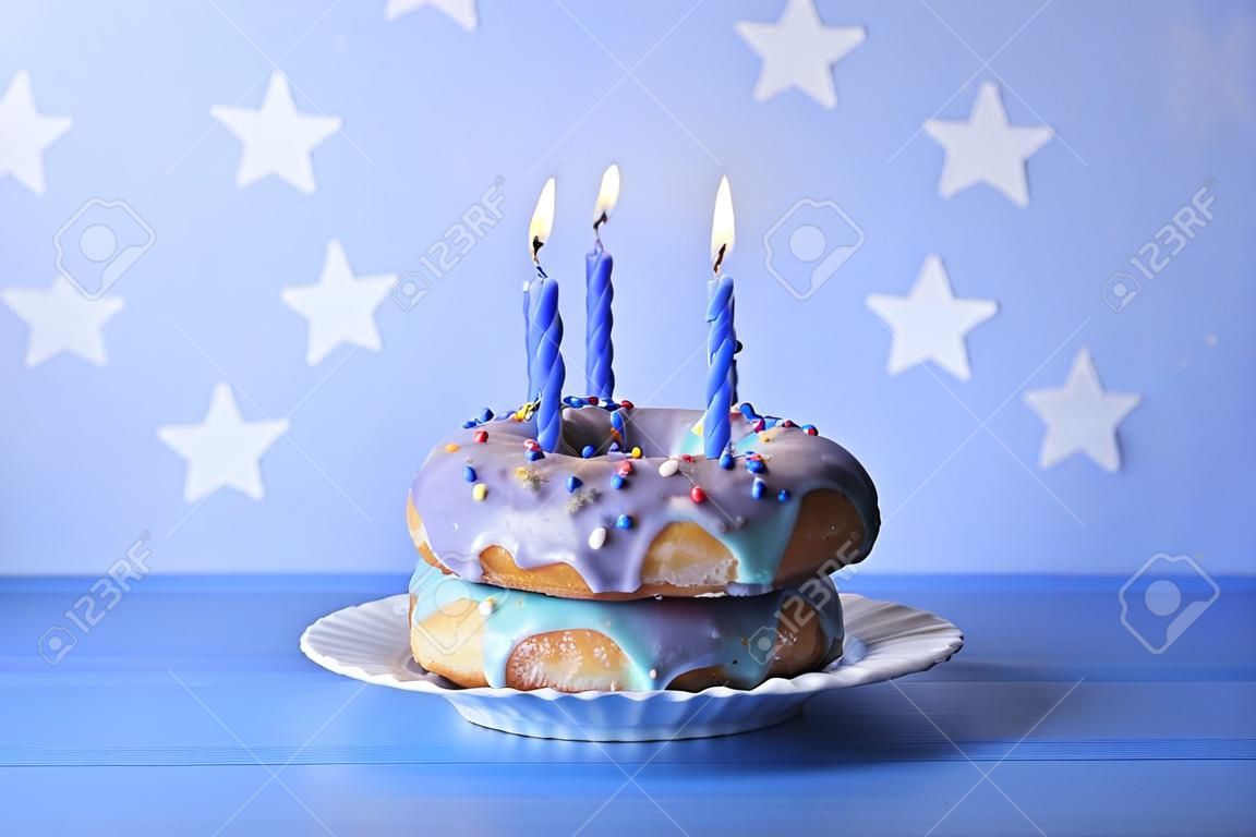 beignets délicieux avec glaçage et bougies d & # 39 ; anniversaire sur la table sur fond clair