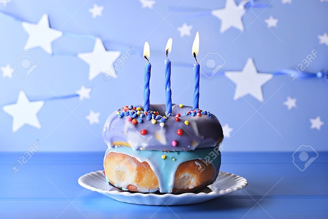 Heerlijke donuts met glazuur en verjaardagskaarsen op tafel op heldere achtergrond