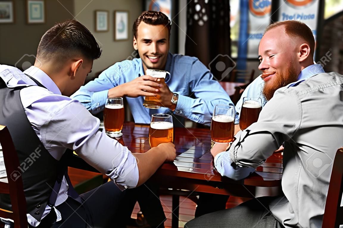 Hombres jóvenes bebiendo cerveza y hablando en el café