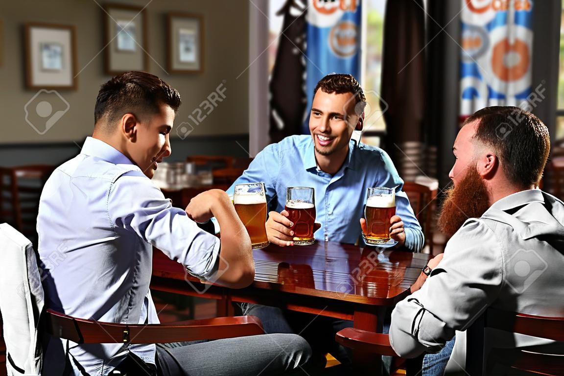 Hombres jóvenes bebiendo cerveza y hablando en el café