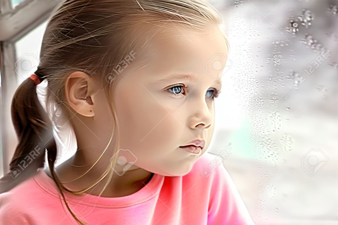 Close up view of little girl looking out of window