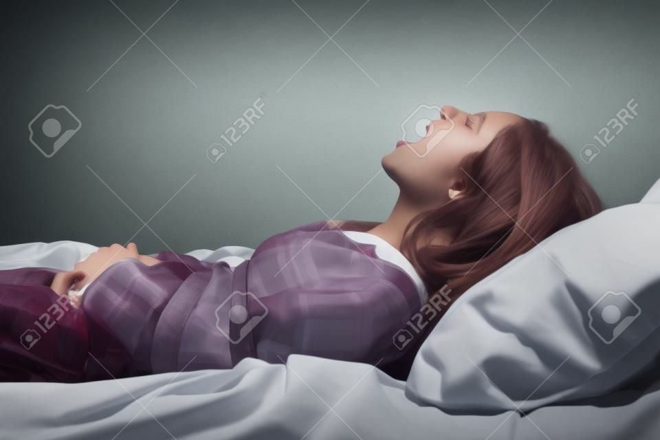 Garota gritando amarrado com cinto na cama. Conceito de paralisia do sono
