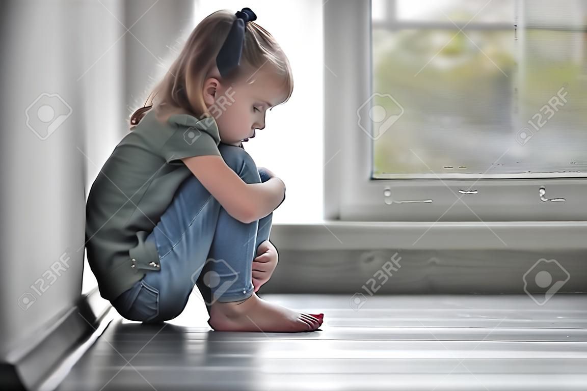 Sad little girl sitting on floor indoors