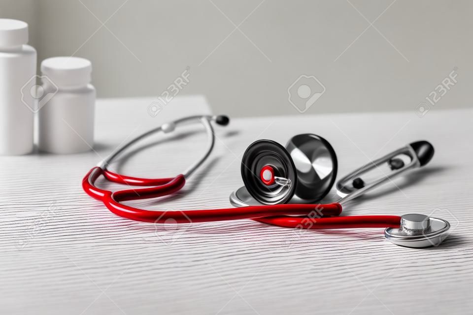 Medical stethoscope and red heart with plaster on light table. Cardiology concept