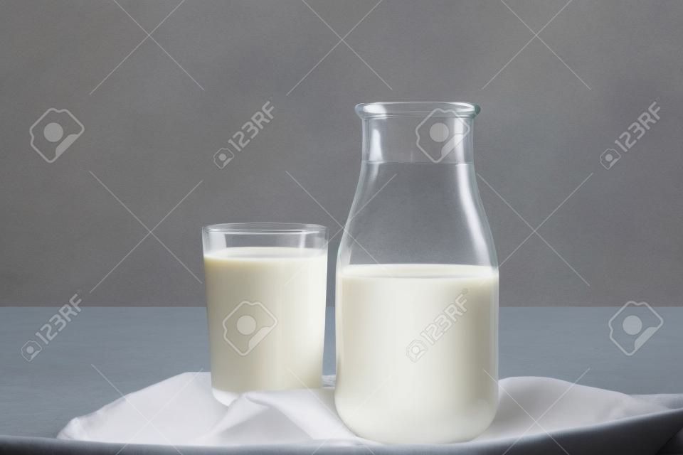 Bottle and glass of tasty milk on light table