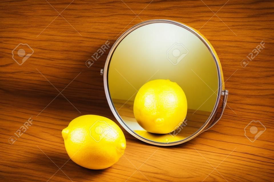 Zitrone, die ihre Reflexion im Spiegel auf Holzhintergrund betrachtet