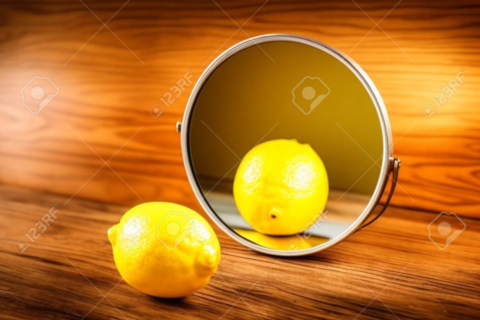 Zitrone, die ihre Reflexion im Spiegel auf Holzhintergrund betrachtet