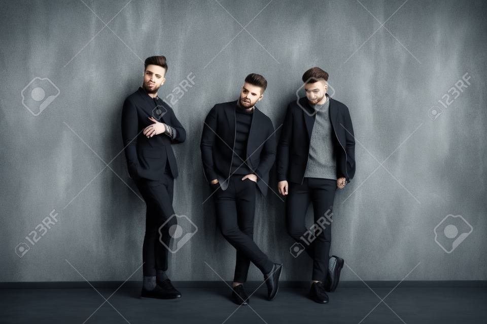 Fashionable young men near gray wall