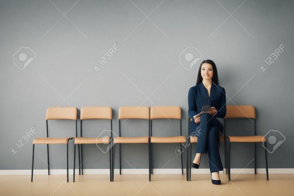 Młoda kobieta czeka na rozmowę kwalifikacyjną w pomieszczeniu