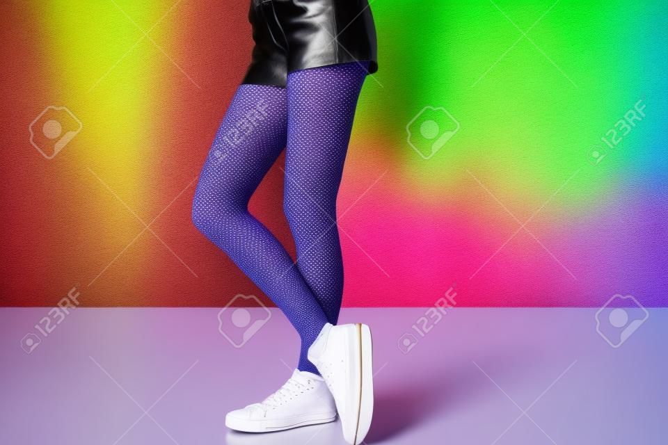 Stijlvolle jonge vrouw in schoenen en panty's in de buurt van kleur muur