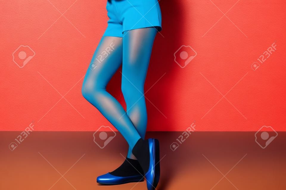 Stijlvolle jonge vrouw in schoenen en panty's in de buurt van kleur muur
