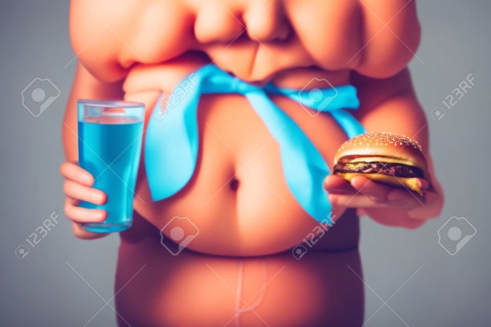 Chica con sobrepeso con hamburguesa poco saludable y bebida sobre fondo de color
