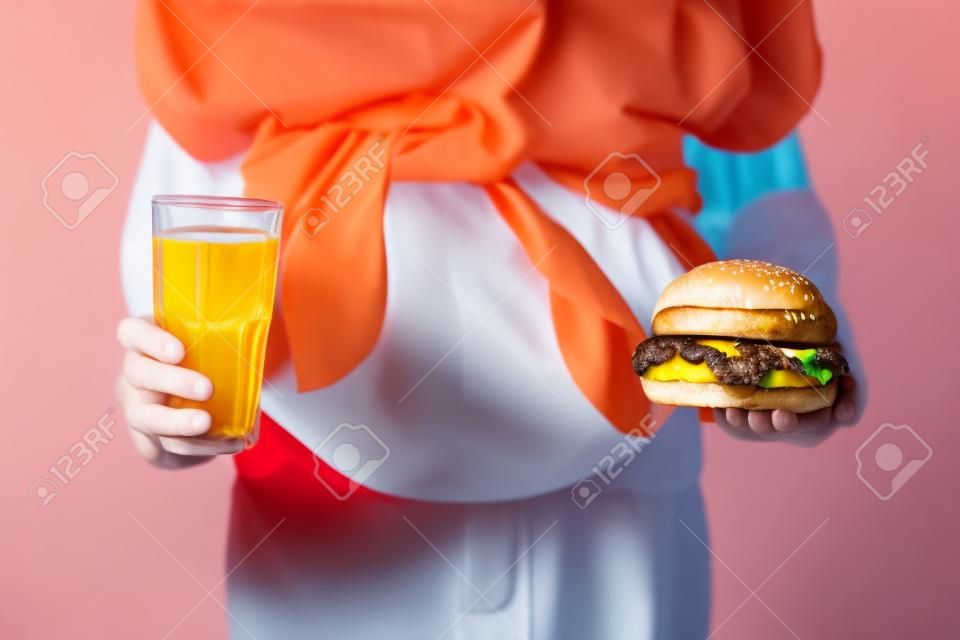 Overweight girl with unhealthy burger and drink on color background