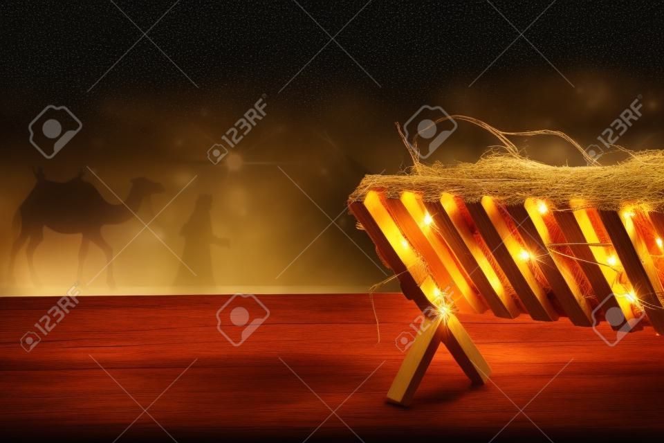 Drewniany żłóbek z sianem na stole w nocy. koncepcja świątecznej historii