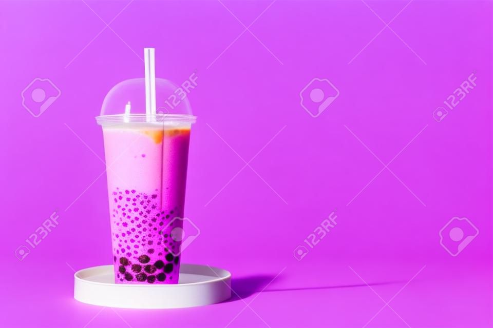 Plastic cup of tasty bubble tea on purple background
