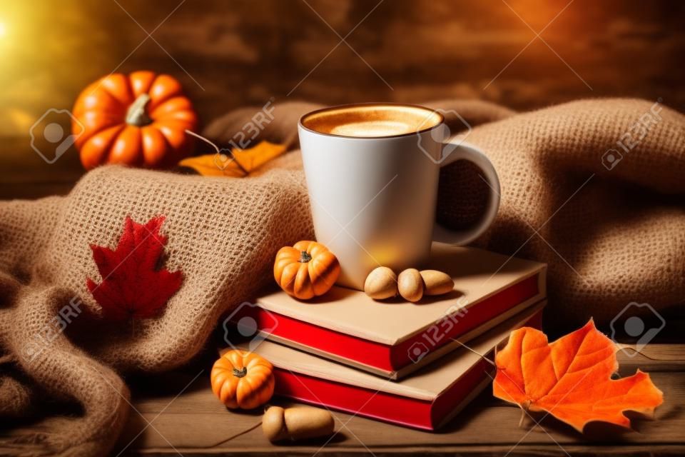 Cup of tasty coffee, books and autumn decor on wooden background