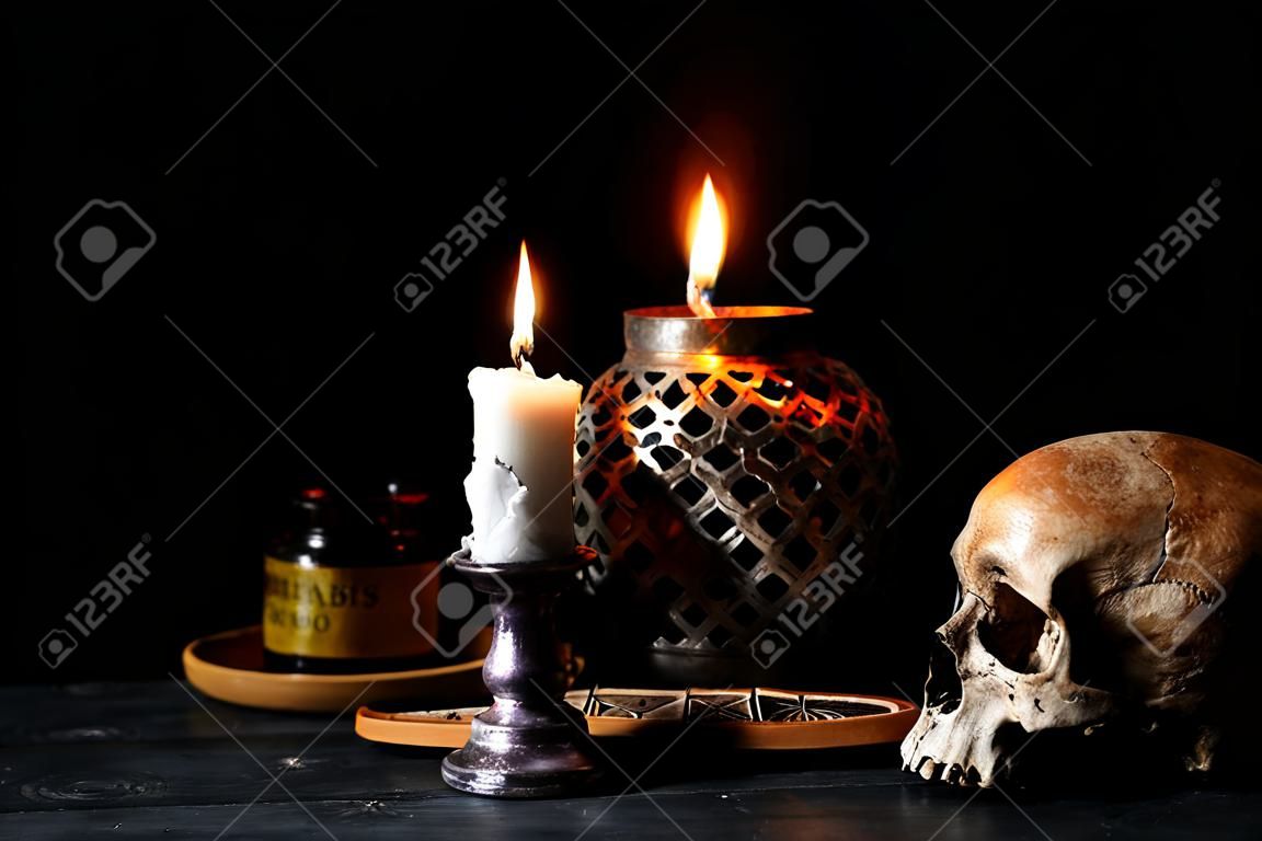 Atributos ardentes da vela, do scull e da magia para o ritual no fundo escuro