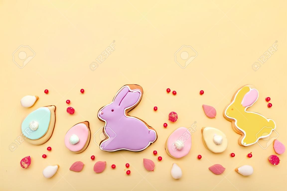 Composition with delicious Easter cookies in shape of bunny, candies and sprinkles on beige background