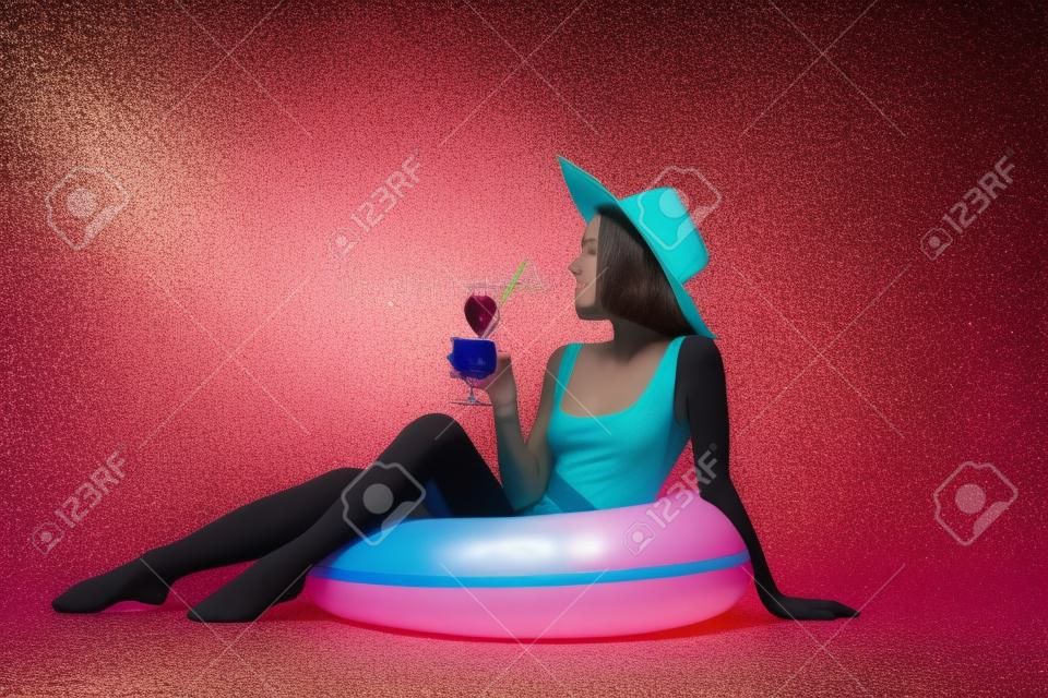 Jeune femme avec cocktail et anneau gonflable sur fond de couleur