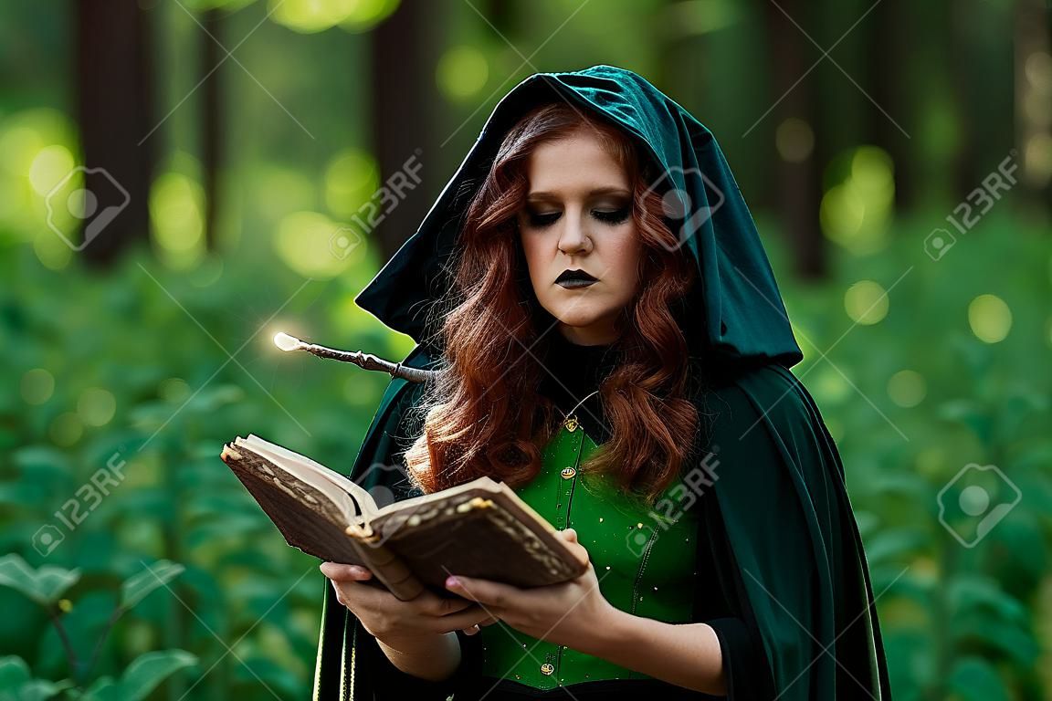 Bruja joven con libro de hechizos en bosque verde
