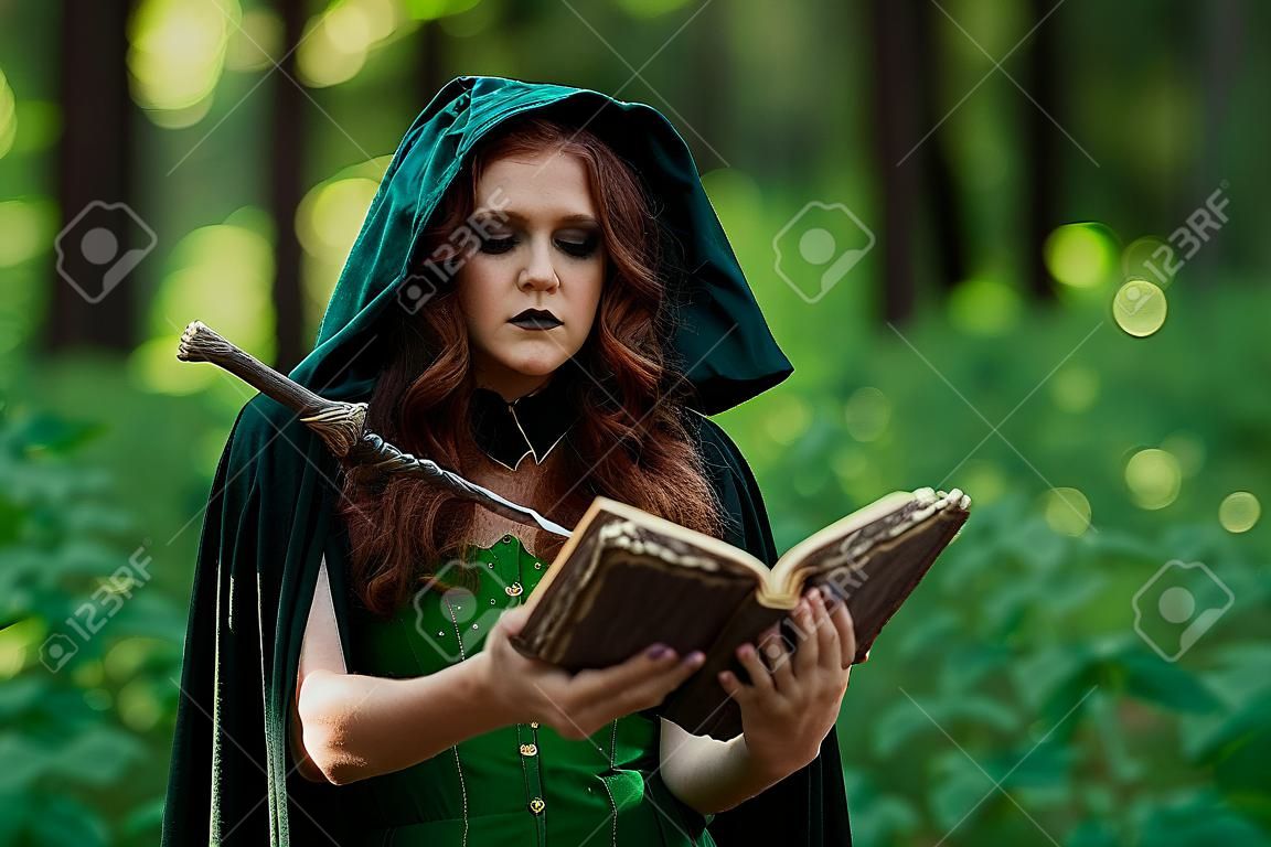 Bruja joven con libro de hechizos en bosque verde