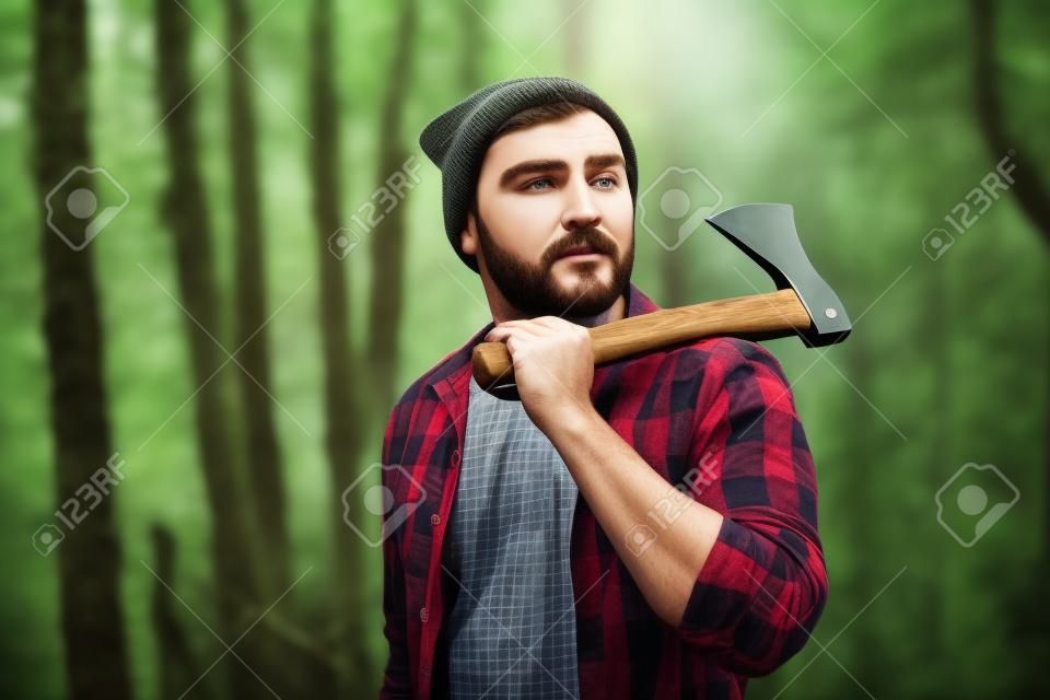Handsome lumberjack with ax in the forest