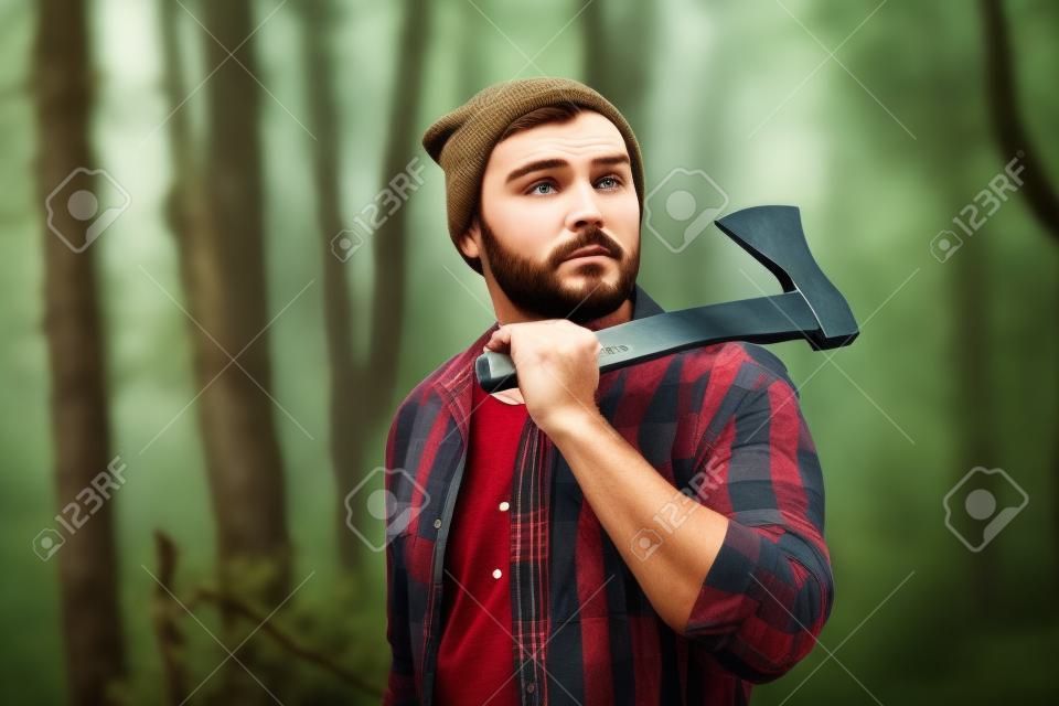 Handsome lumberjack with ax in the forest