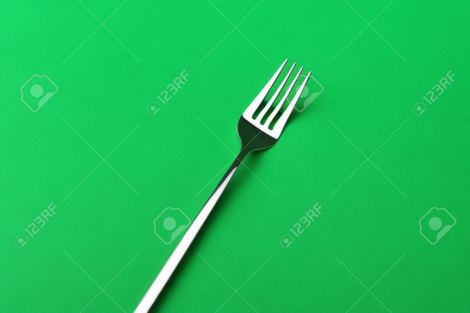 Stainless steel fork on green background