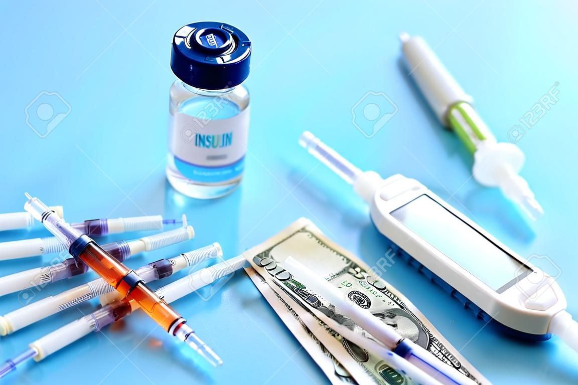 Syringes with money, glucometer and insulin on blue background, closeup. Expensive medicine concept