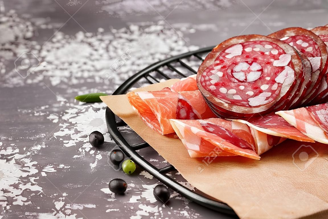 Griglia con fette di gustoso salame su sfondo grigio