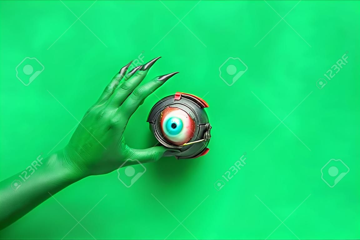 Hand of witch with cauldron and eye on green background. halloween celebration