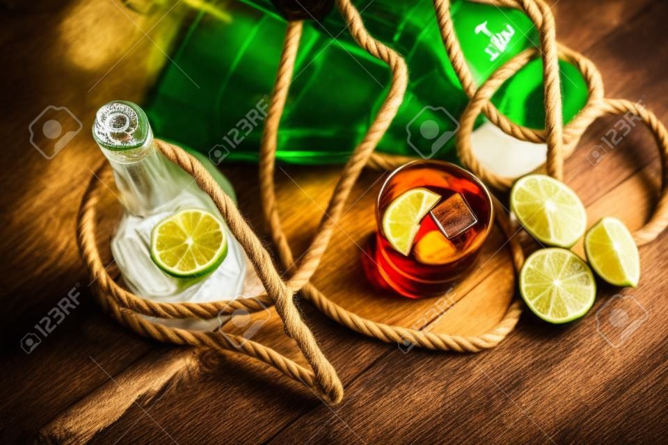 A bottle of whiskey, rum, brandy, lime on a wooden background