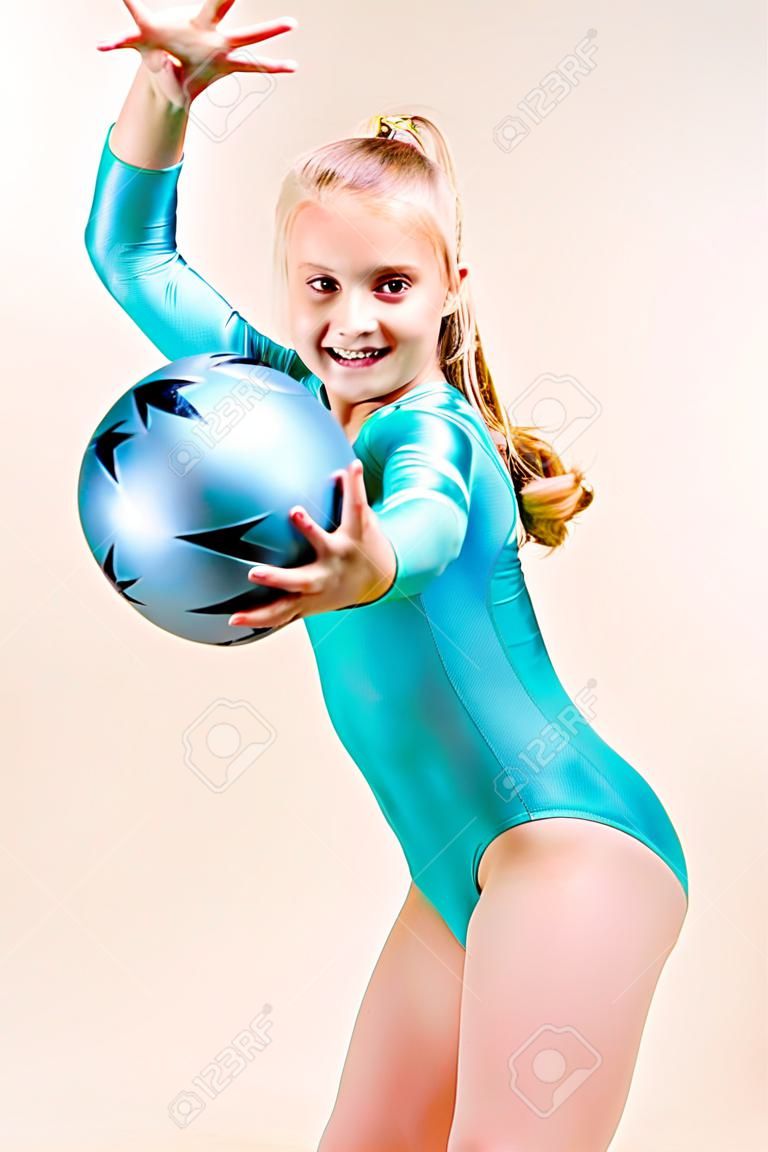 Teenage Turnerin mit Ball auf grauem Hintergrund