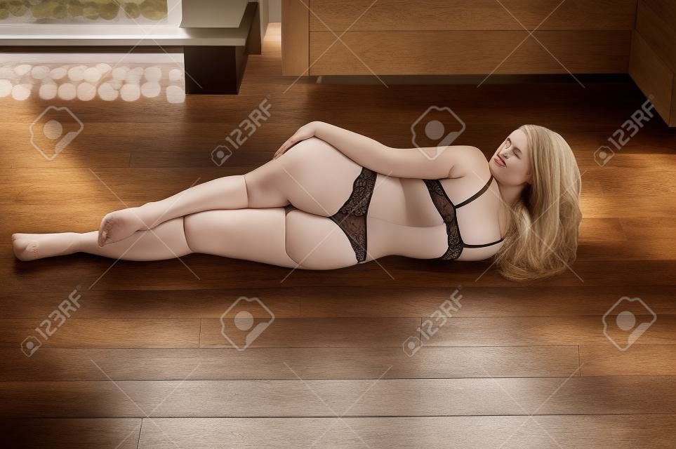 plus la taille des femmes en lingerie couché sur le côté, le dos sur le plancher en bois