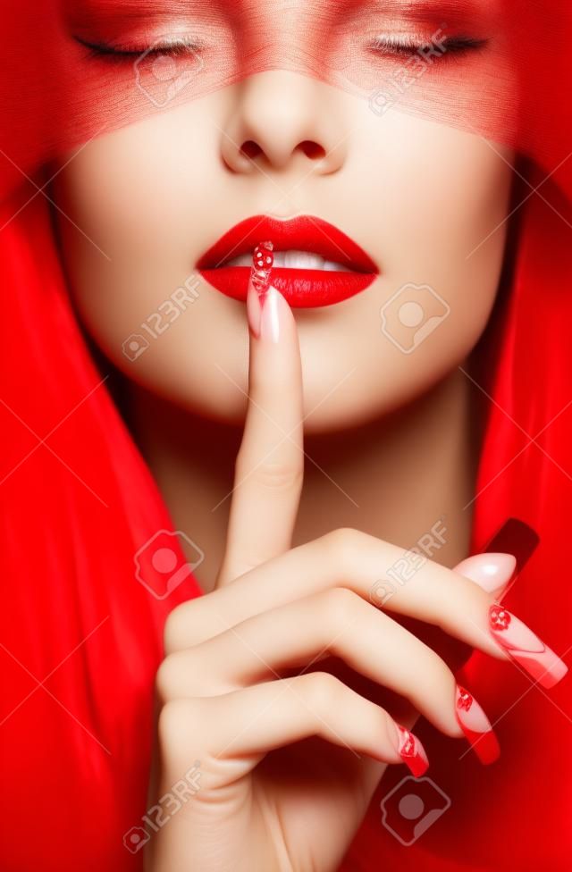 Woman part of face with eyes closed by red ribbon and with red french acrylic nails manicure