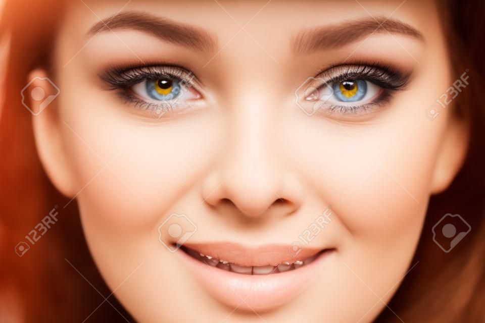 Closeup tiro de rosto sorridente feminino humano. Mulher com rosto natural e maquiagem de beleza de olhos.