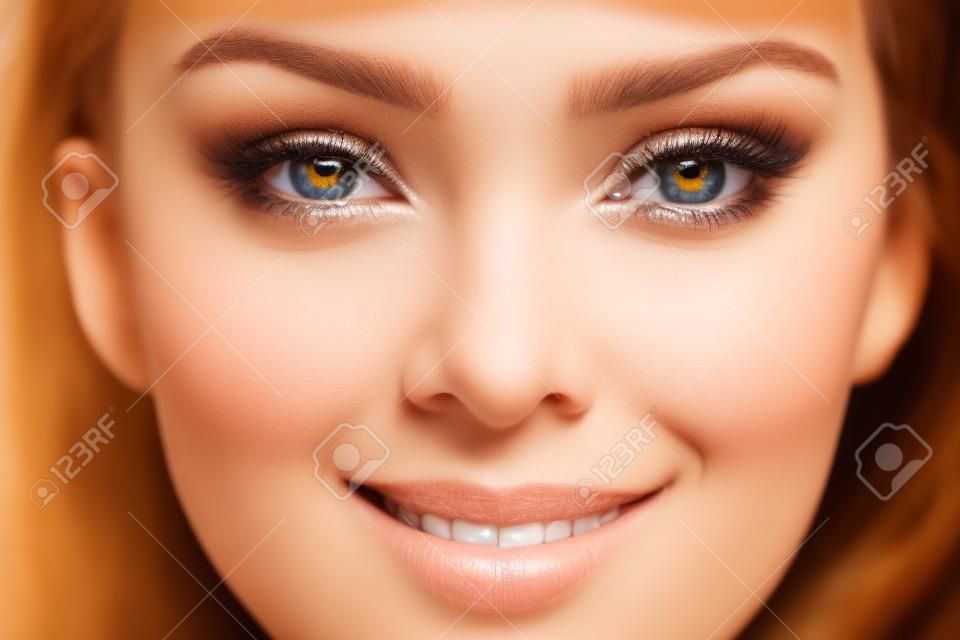 Close-up shot van menselijke vrouwelijke glimlachende gezicht. Vrouw met natuurlijke gezicht en ogen schoonheid make-up.