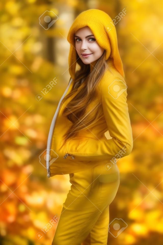 黄色叶子的美丽的女孩画象。户外的