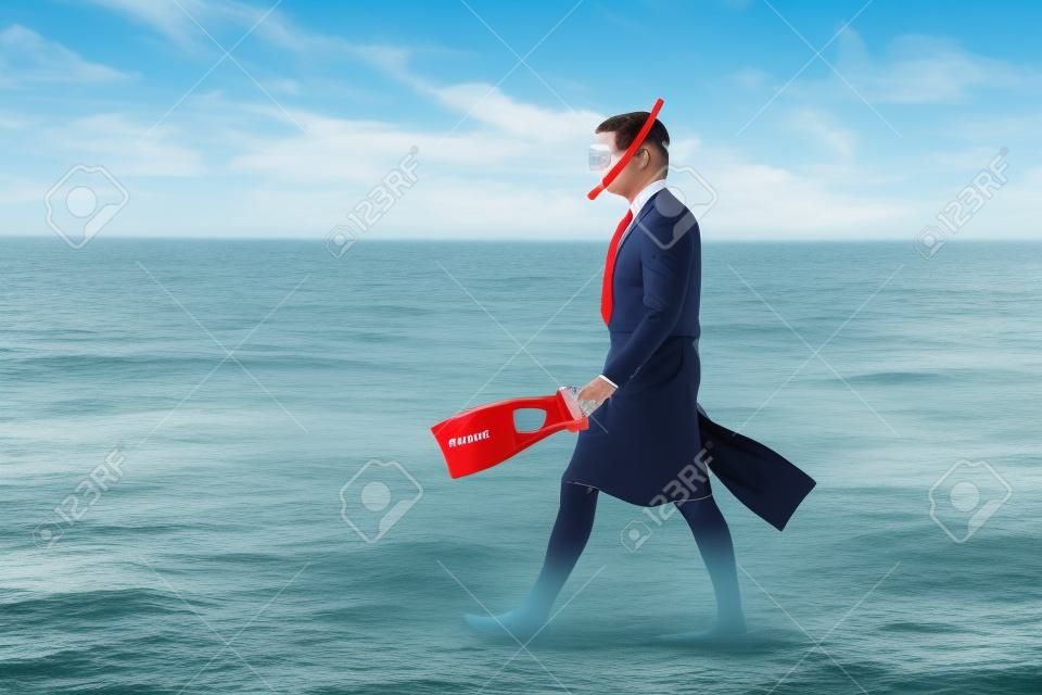 Hombre de negocios entrar en las aguas del océano usando la máscara de los ronquidos con aletas y el uso de ropa formal, con corbata roja de entrada del agua en la playa