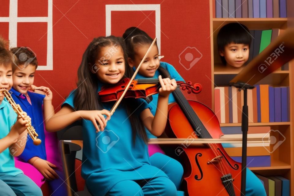 Grupo de crianças tocando instrumentos musicais dentro de casa